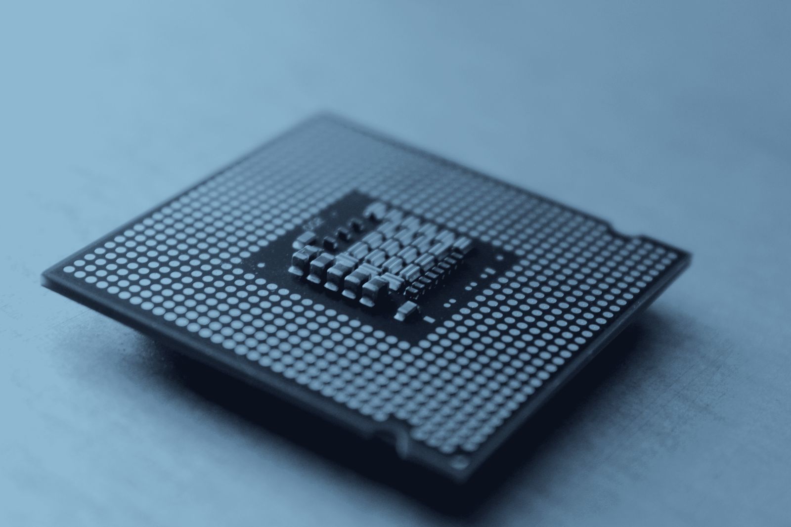 Macro photograph of the underside of a CPU, golden pins and capacitors